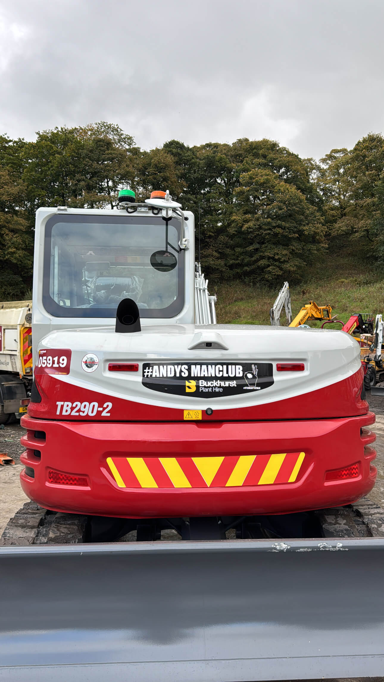 A red and white Takeuchi excavator, stickered with Andys Man Club branding.