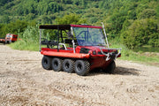 A red all terrain vehicle on a gravel ground with a woodland backdrop.  