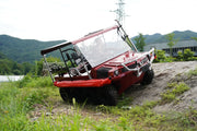 Red all-terrain vehicle on a dirt path with mountains in the background
