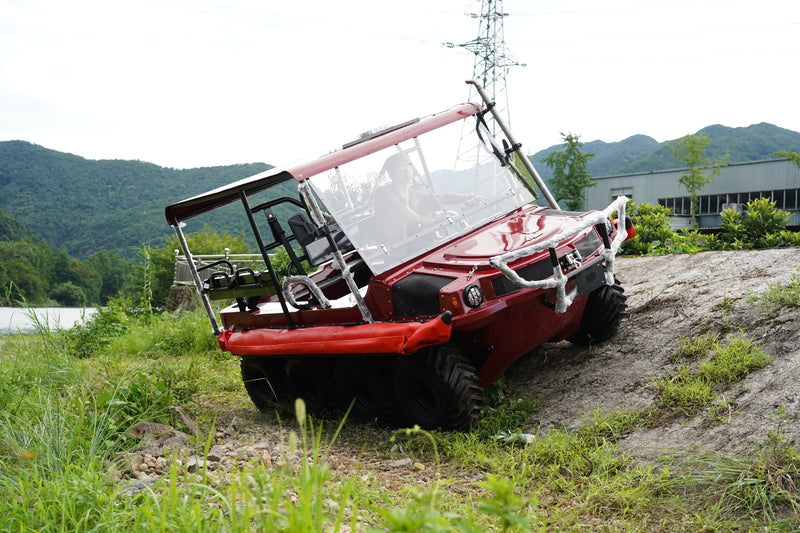 Red all-terrain vehicle on a dirt path with mountains in the background