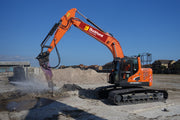 An orange Doosan 25T excavator with a demolition attachment is working on a construction site.