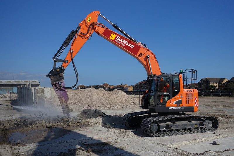 An orange Doosan 25T excavator with a demolition attachment is working on a construction site.