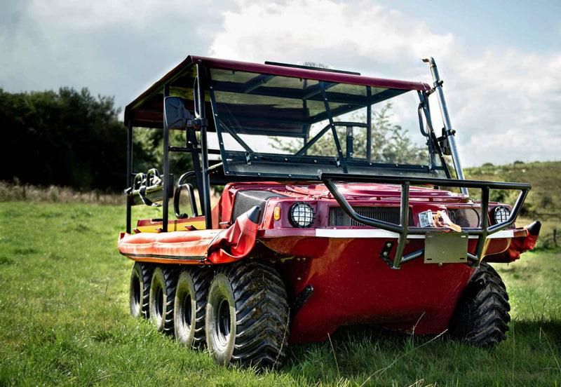 Red off-road vehicle on grassy terrain. 
